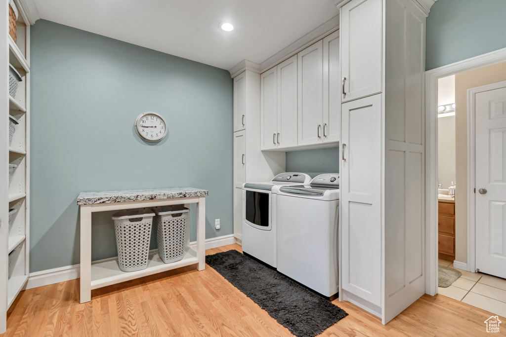 Washroom featuring washing machine and dryer, cabinet space, light wood-style floors, and recessed lighting