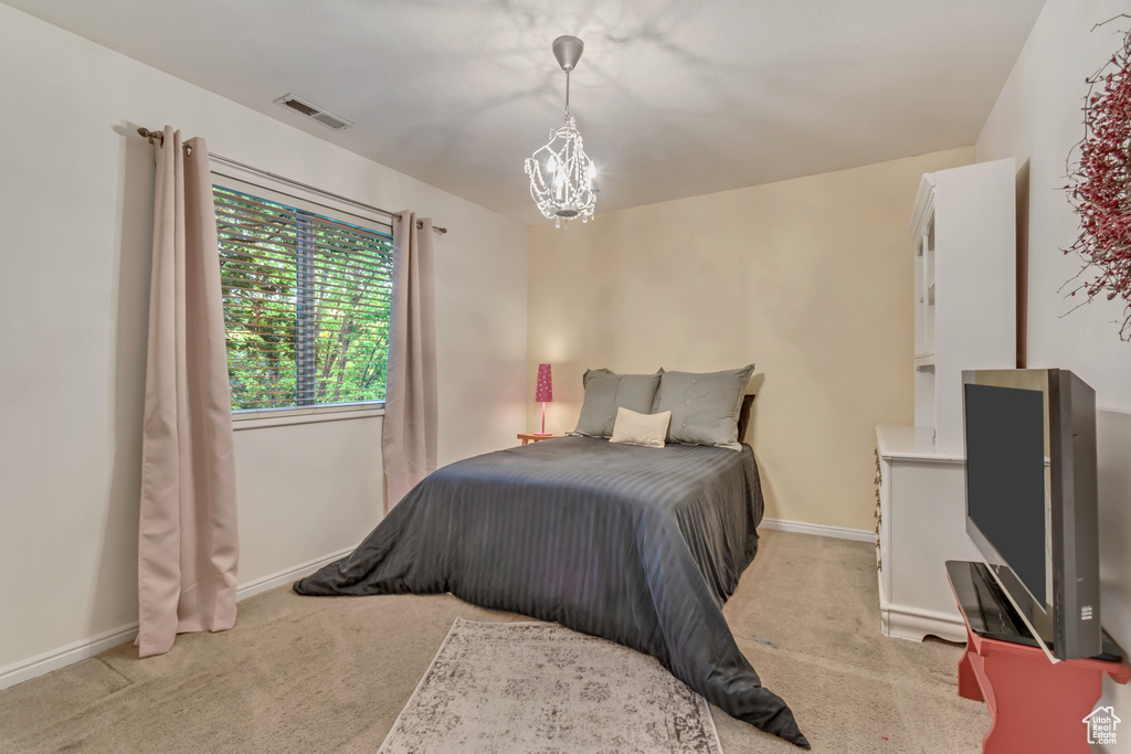 Bedroom featuring a chandelier, light carpet, and baseboards