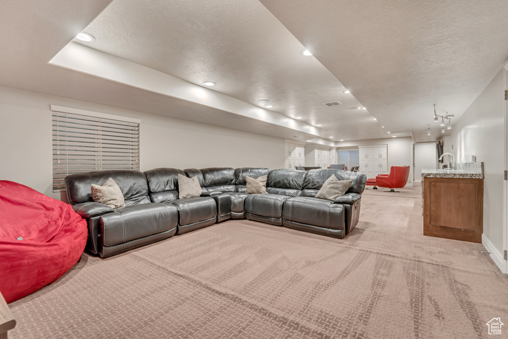Living area with light carpet, a textured ceiling, recessed lighting, a raised ceiling, and baseboards