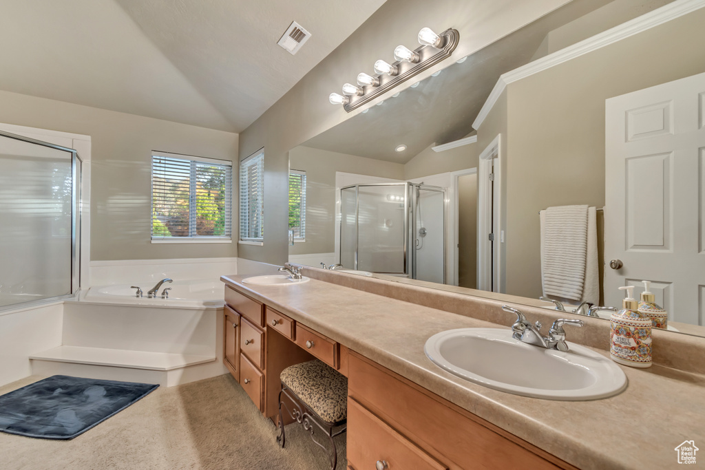 Full bathroom featuring lofted ceiling, a shower stall, a garden tub, and double vanity