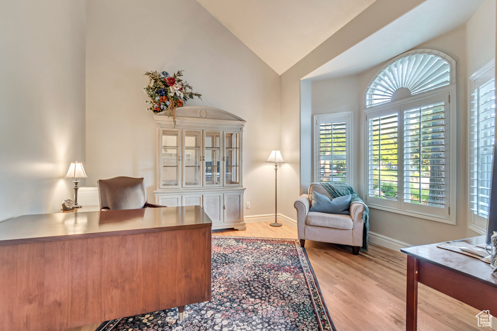 Office space with vaulted ceiling, light wood-style flooring, and baseboards