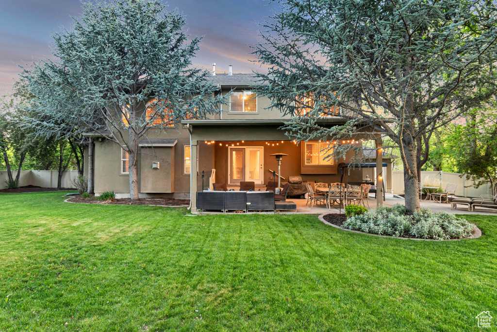 Back of house at dusk featuring an outdoor living space, stucco siding, and a patio area
