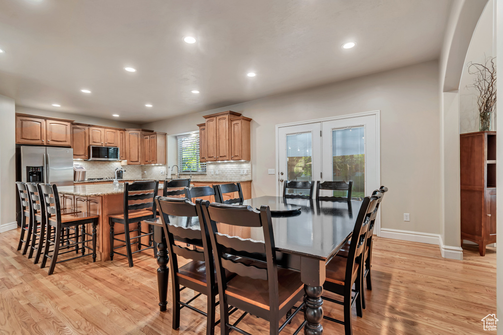 Dining room with light wood-style floors, recessed lighting, baseboards, arched walkways, and french doors