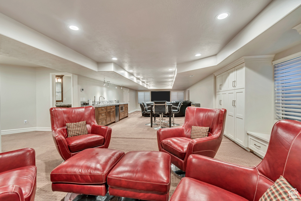 Living room with light carpet, bar with sink, baseboards, and recessed lighting