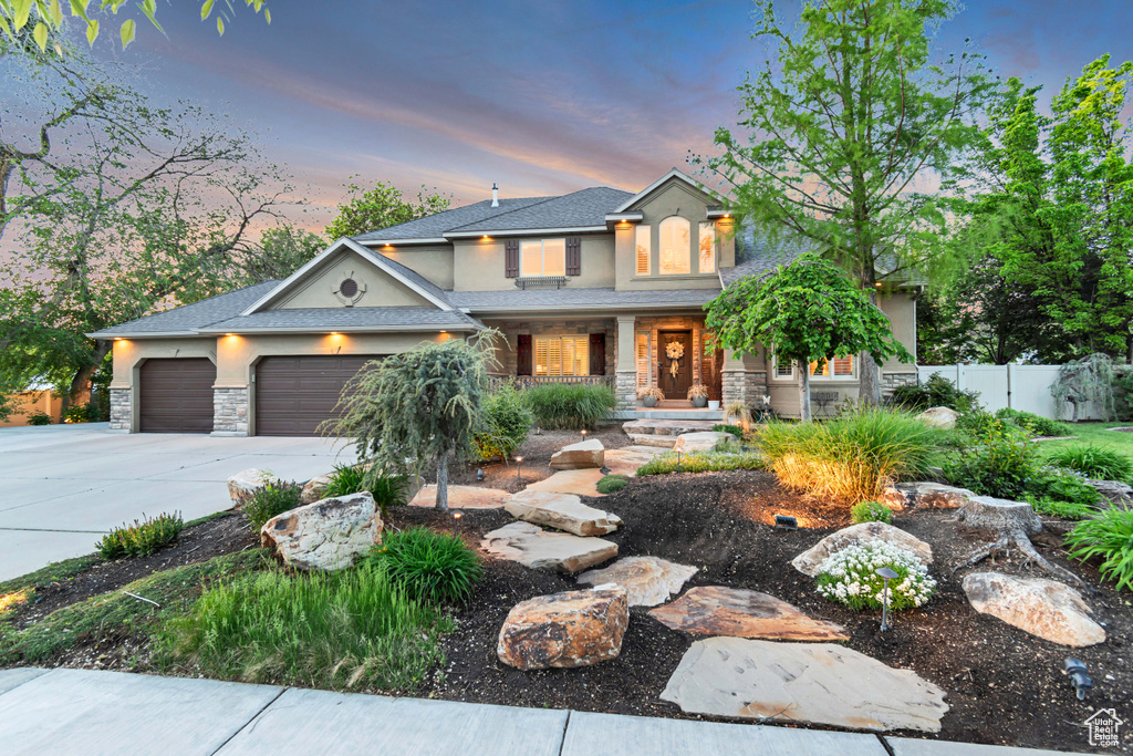 View of front of property with stone siding, fence, and stucco siding