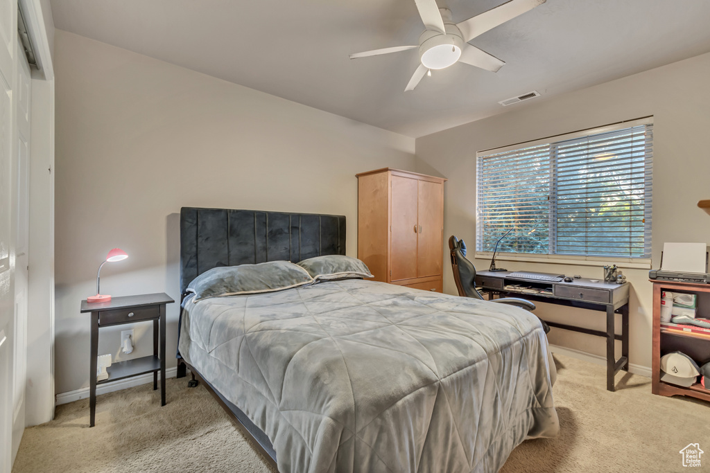 Bedroom with light colored carpet, baseboards, and a ceiling fan