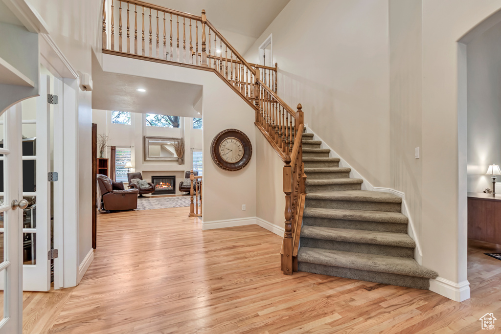 Entrance foyer with wood finished floors, arched walkways, stairs, a glass covered fireplace, and a high ceiling