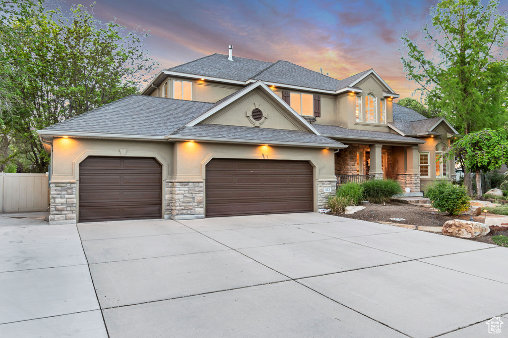 View of front of home with stucco siding, stone siding, and covered porch