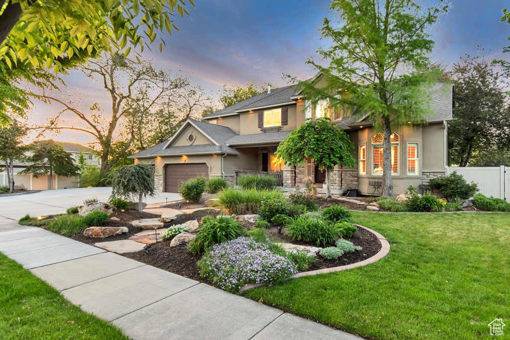 View of front of property with stucco siding, stone siding, driveway, and a garage