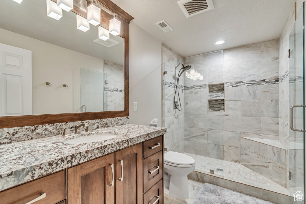 Bathroom with a stall shower, vanity, toilet, and recessed lighting