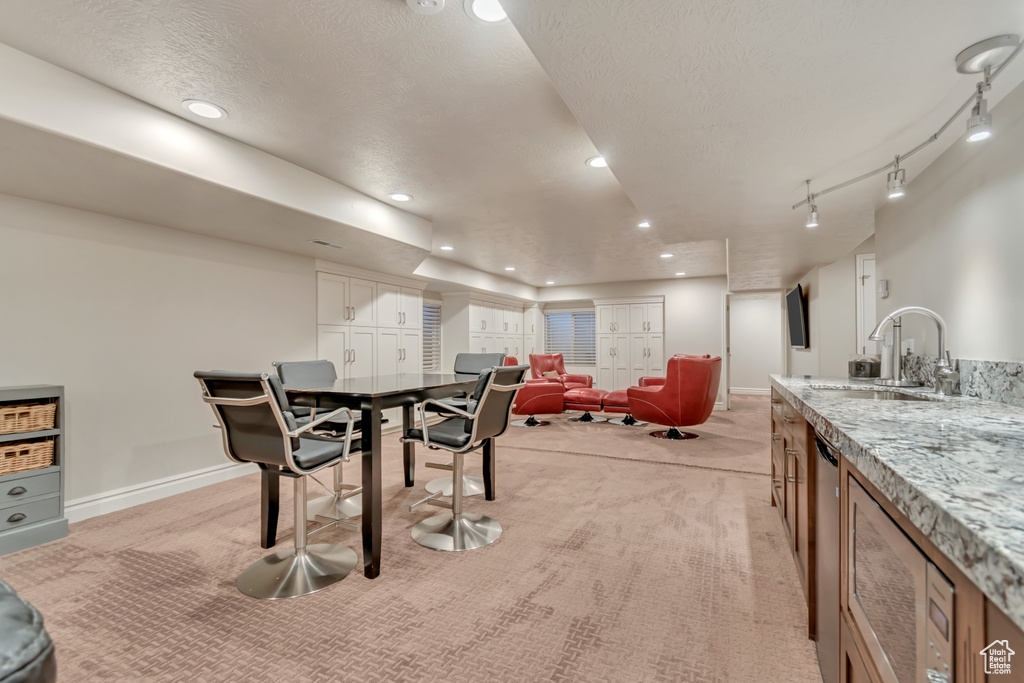 Dining area with light colored carpet, baseboards, a textured ceiling, and recessed lighting