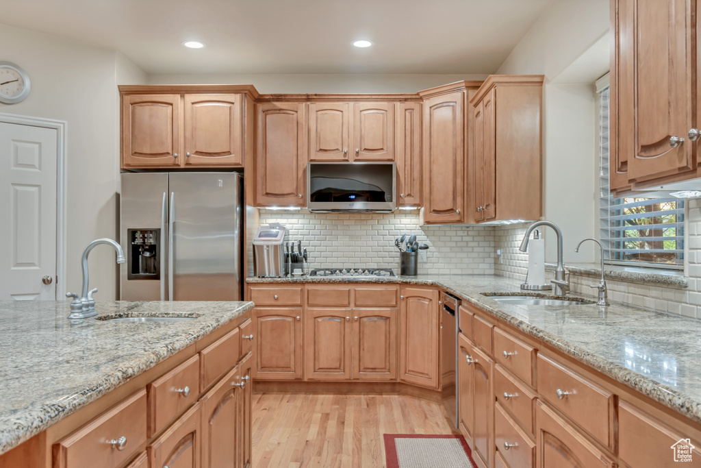 Kitchen featuring stainless steel appliances, a sink, light stone countertops, light wood-style flooring, and recessed lighting