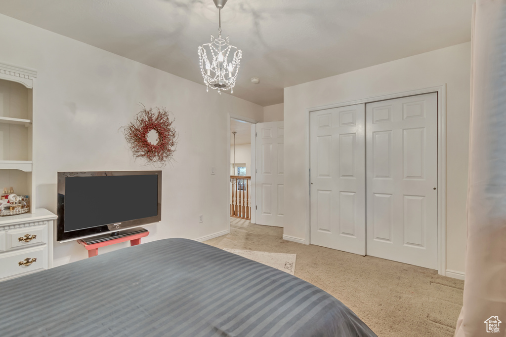 Bedroom with a chandelier, light colored carpet, a closet, and baseboards