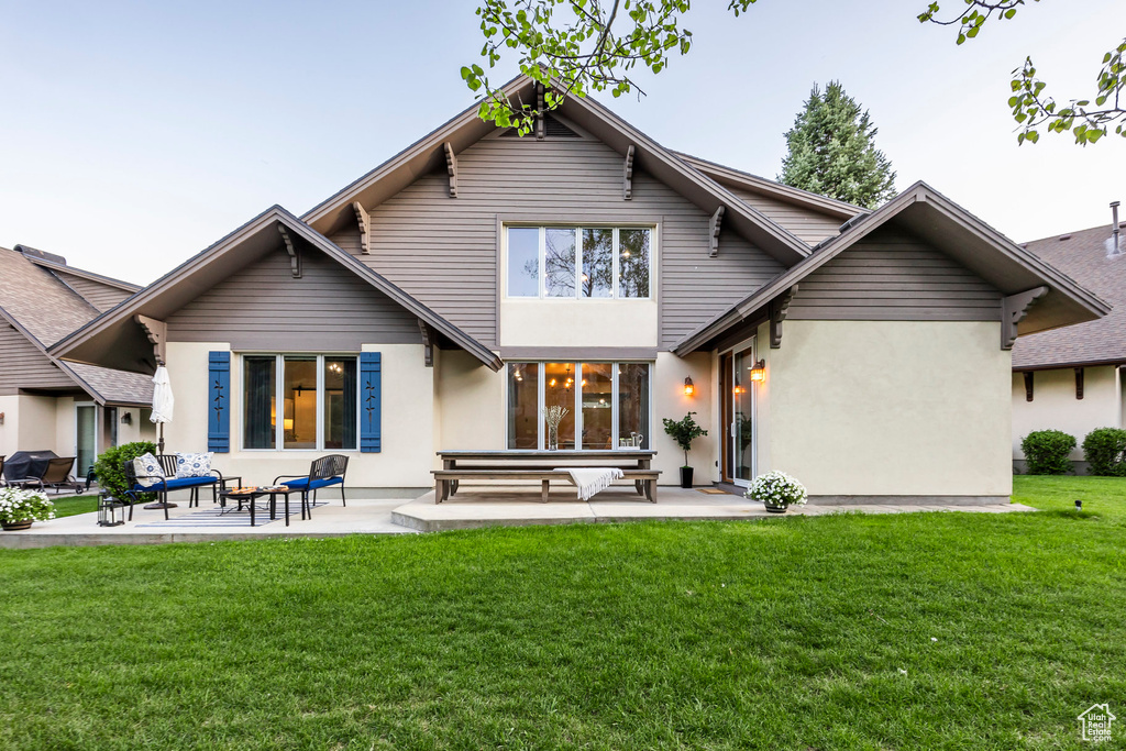 Rear view of house with a patio area, a yard, and stucco siding