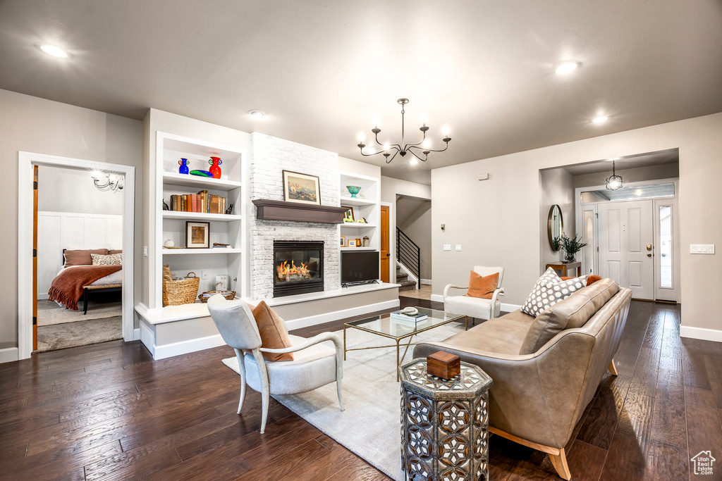 Living area with a chandelier, stairs, baseboards, dark wood-type flooring, and recessed lighting