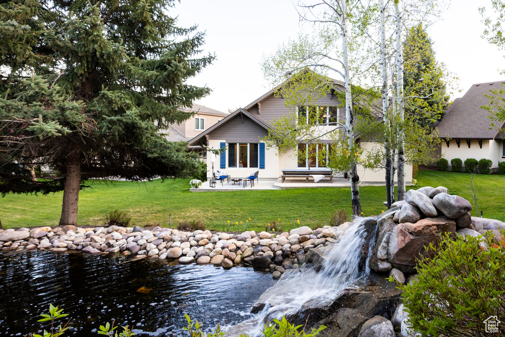 Rear view of property featuring a lawn, a patio, and a balcony