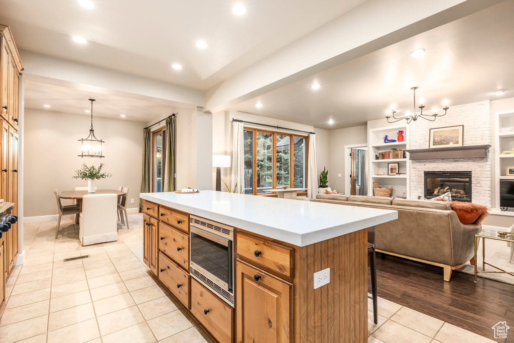 Kitchen featuring stainless steel microwave, a chandelier, recessed lighting, light tile patterned floors, and a breakfast bar area