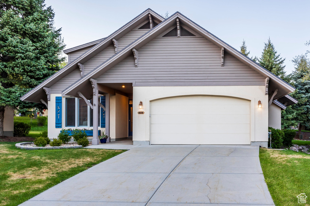 View of front facade featuring an attached garage, driveway, a front lawn, and stucco siding