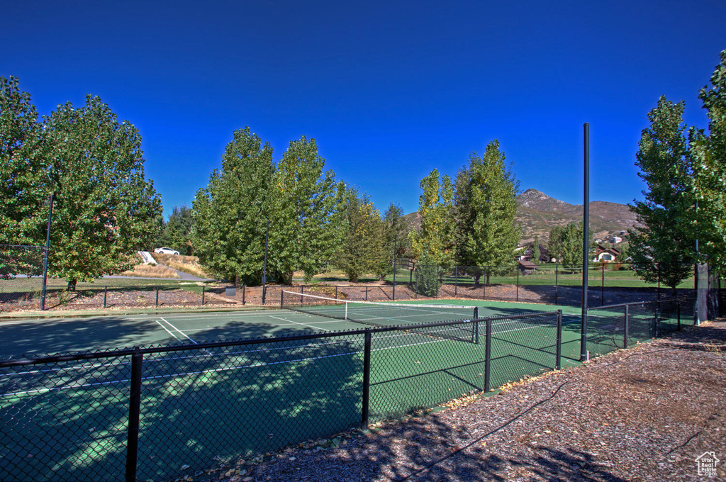 View of tennis court with fence and a mountain view