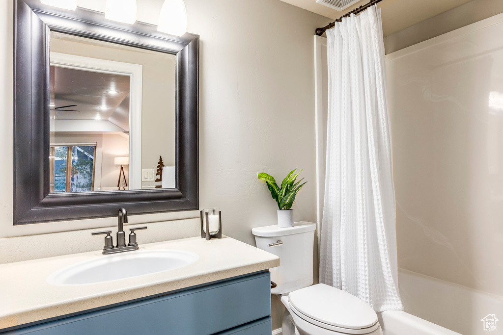 Bathroom with toilet, vanity, and shower / bath combo