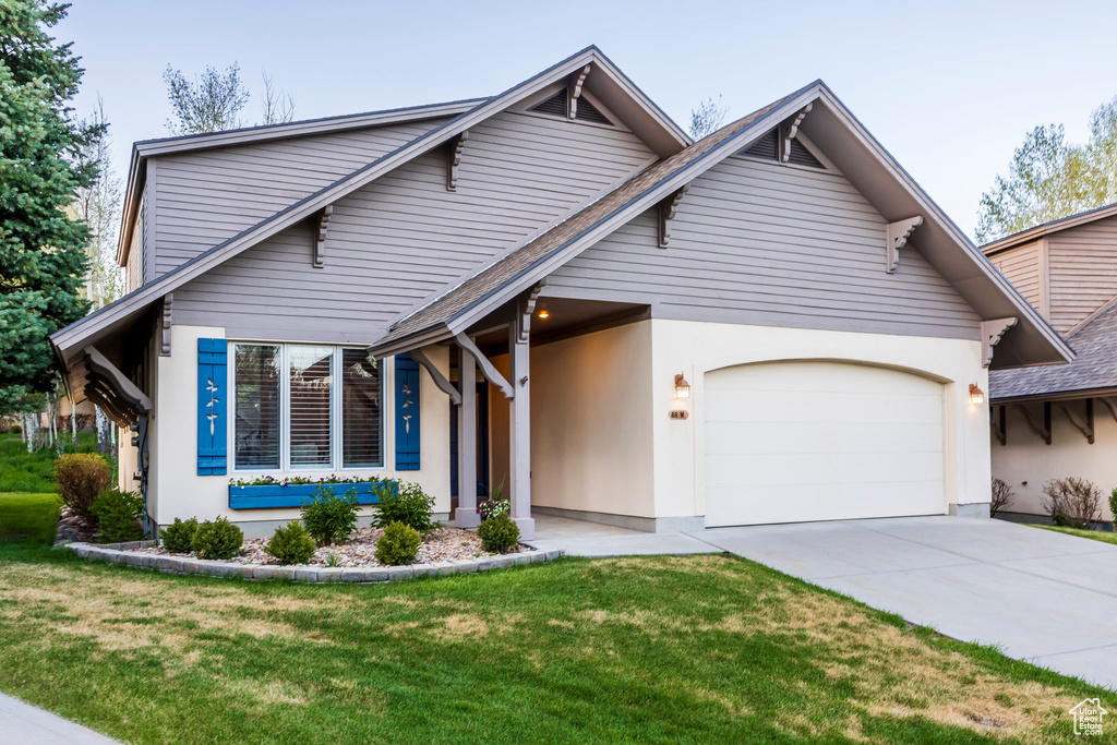 View of front of property with an attached garage, concrete driveway, a front yard, and roof with shingles