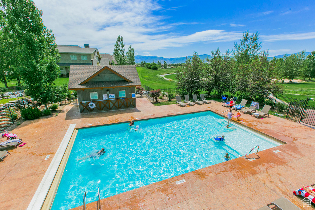 Community pool featuring a patio area, a mountain view, and fence