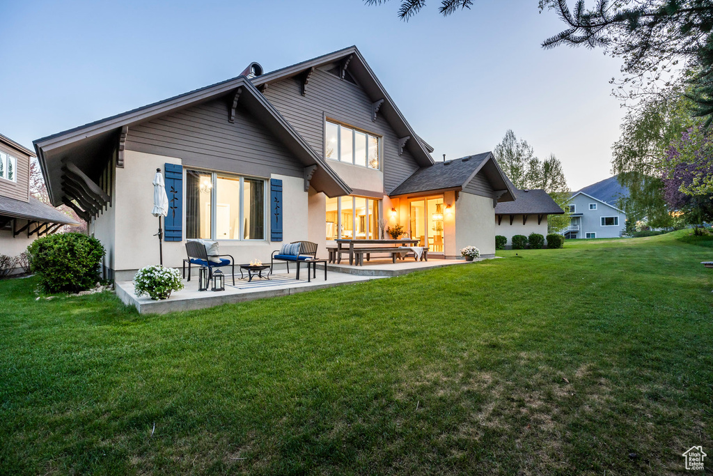 Rear view of property with a patio, a lawn, and stucco siding