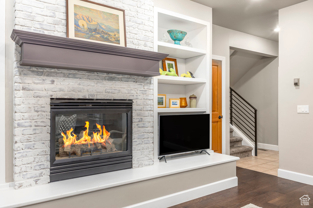 Detailed view of built in shelves, wood finished floors, baseboards, and a brick fireplace