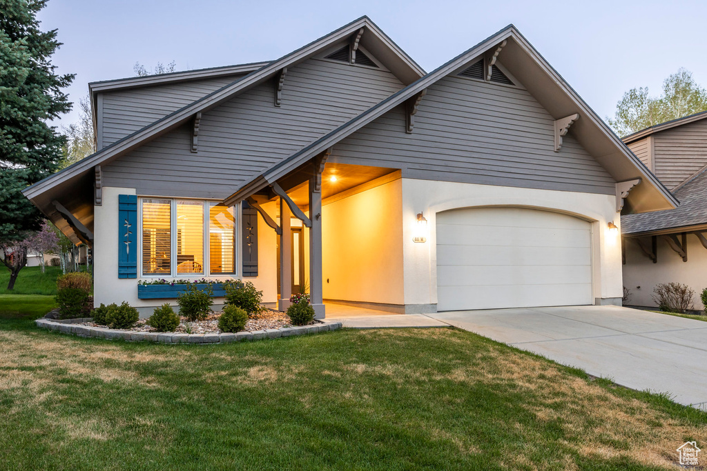 View of front of home with an attached garage, concrete driveway, a front lawn, and stucco siding