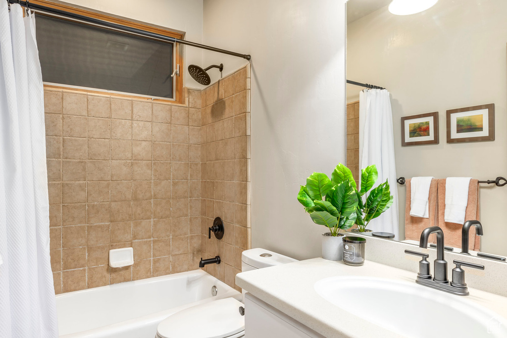 Bathroom with shower / bath combo with shower curtain, toilet, and vanity
