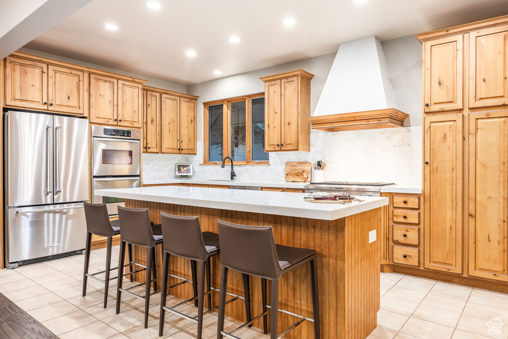 Kitchen featuring appliances with stainless steel finishes, custom exhaust hood, a center island, recessed lighting, and light countertops