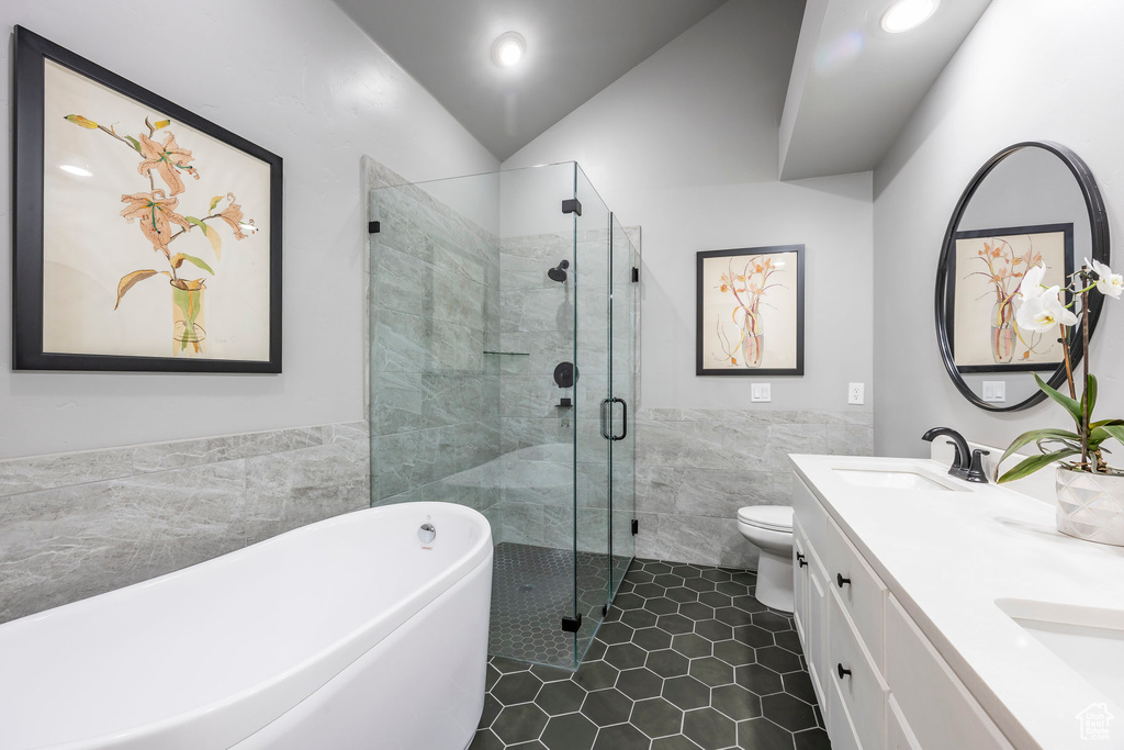 Full bath featuring tile walls, a freestanding tub, a shower stall, tile patterned flooring, and double vanity