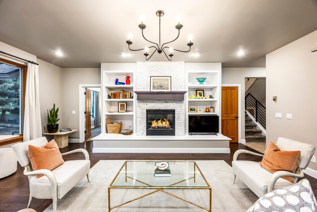 Living room with stairs, wood finished floors, a chandelier, a fireplace, and baseboards