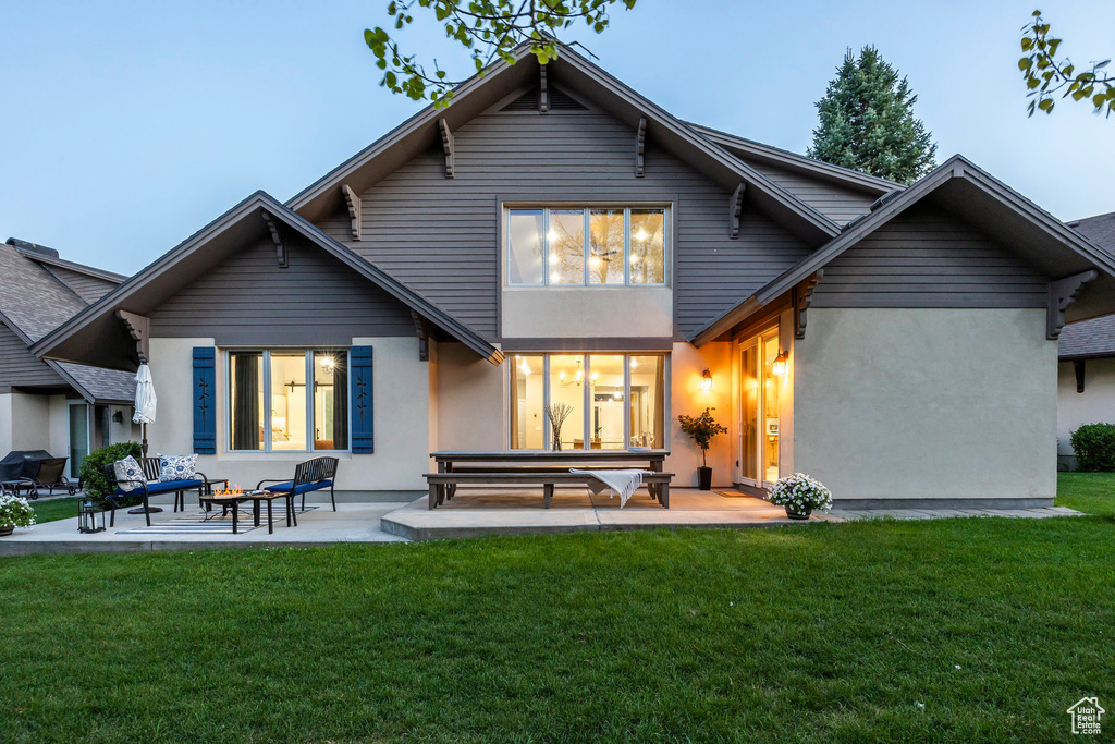 Rear view of property featuring a patio, stucco siding, and a lawn