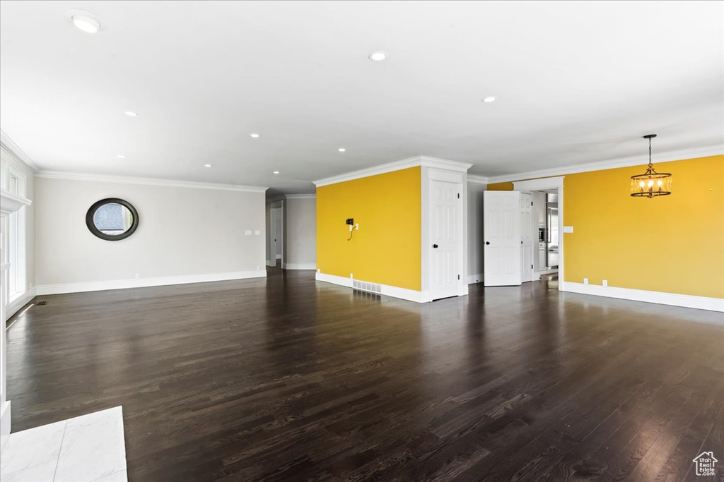 Unfurnished living room featuring baseboards, dark wood-style floors, ornamental molding, and recessed lighting