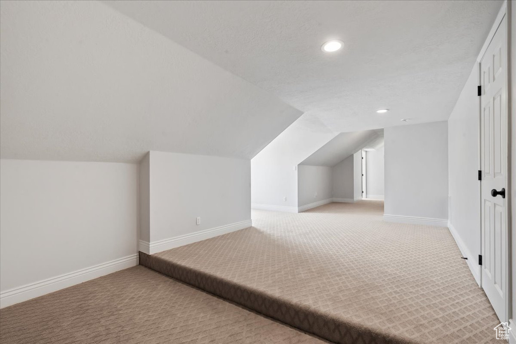Additional living space with light carpet, recessed lighting, vaulted ceiling, and baseboards