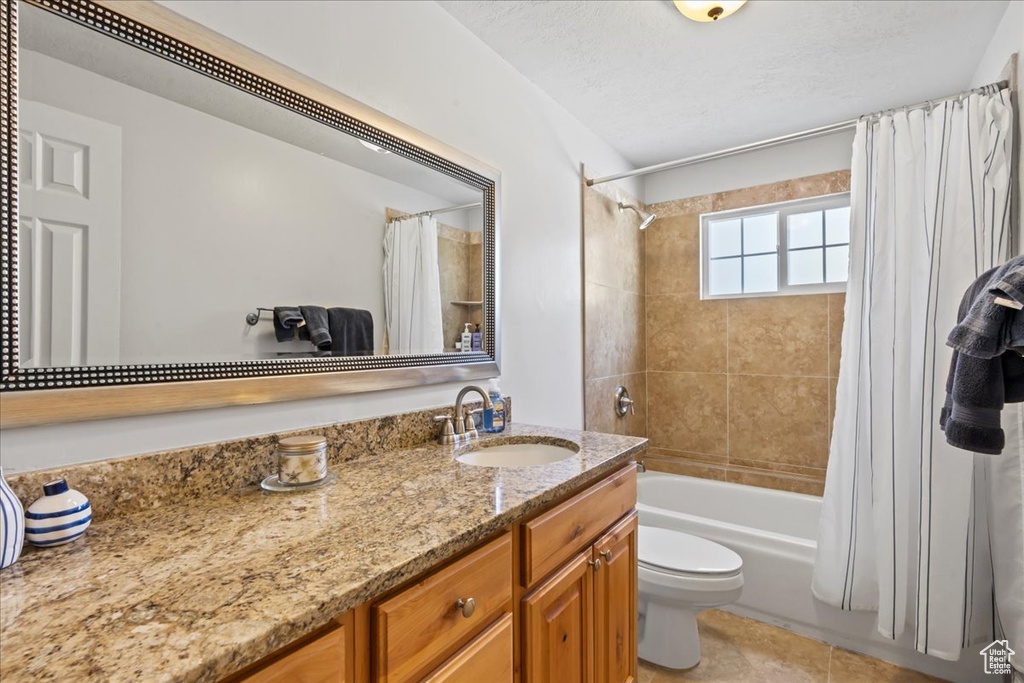 Bathroom featuring vanity, shower / bathtub combination with curtain, toilet, and tile patterned floors