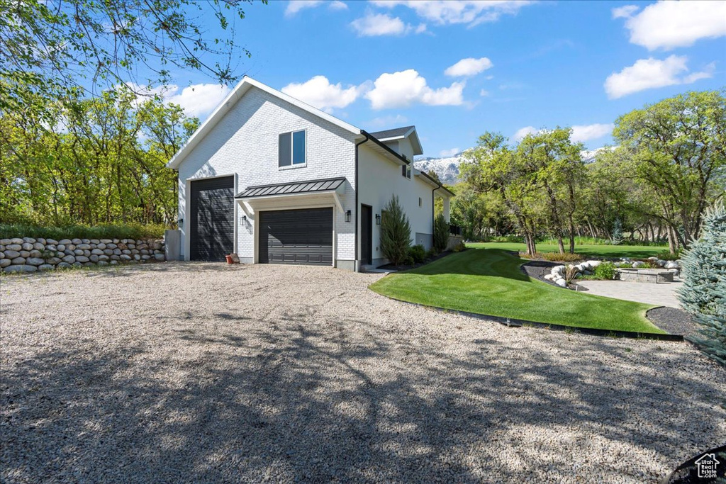View of side of property with driveway, an attached garage, a yard, and brick siding