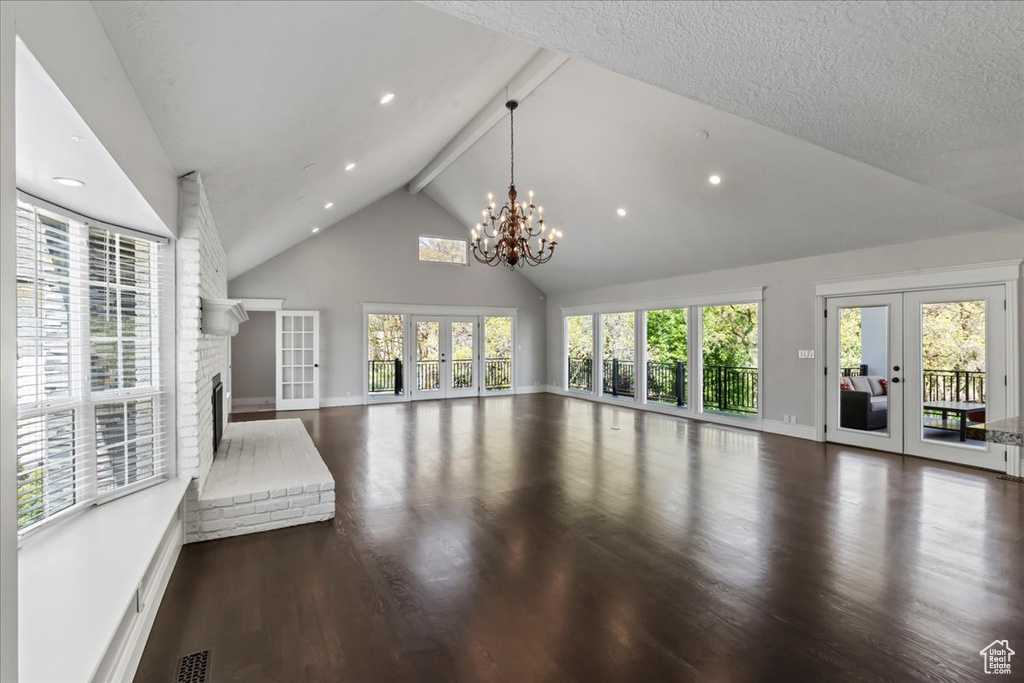 Unfurnished living room featuring high vaulted ceiling, french doors, wood finished floors, baseboards, and a fireplace