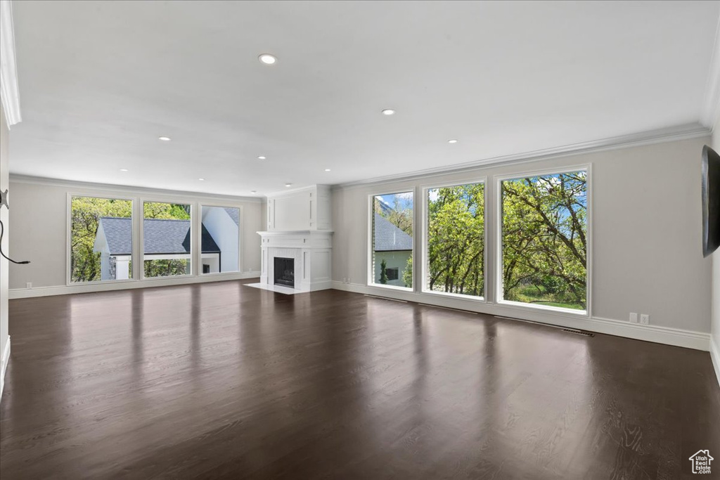 Unfurnished living room with a fireplace with flush hearth, dark wood finished floors, ornamental molding, baseboards, and recessed lighting