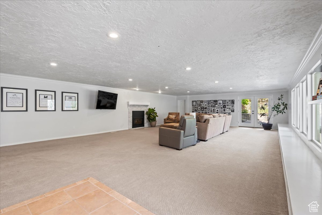 Carpeted living room with a fireplace, recessed lighting, crown molding, baseboards, and french doors
