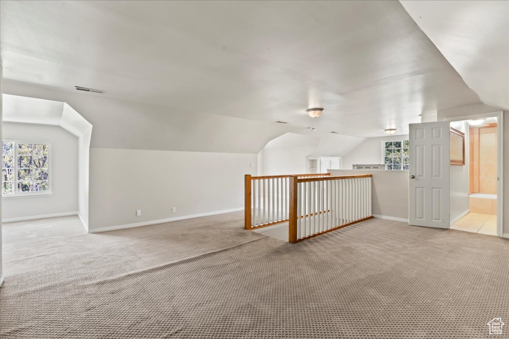 Additional living space with light colored carpet, lofted ceiling, and baseboards