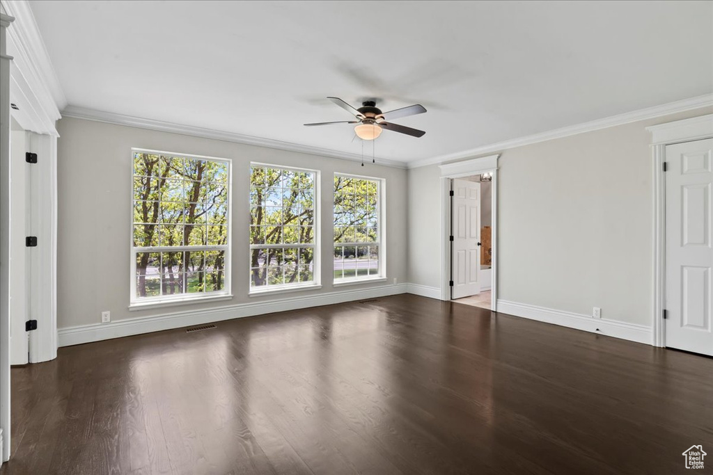 Spare room with ceiling fan, baseboards, crown molding, and wood finished floors