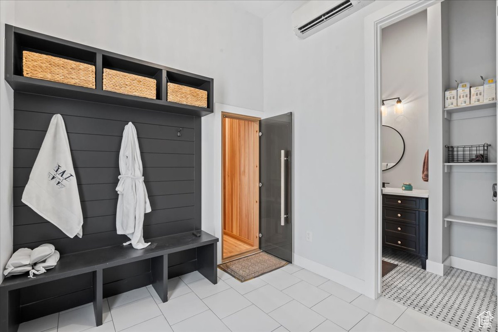 Mudroom with an AC wall unit, baseboards, and a high ceiling
