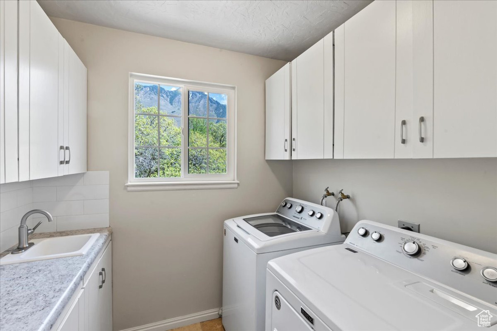 Clothes washing area with cabinet space, washer and dryer, and baseboards