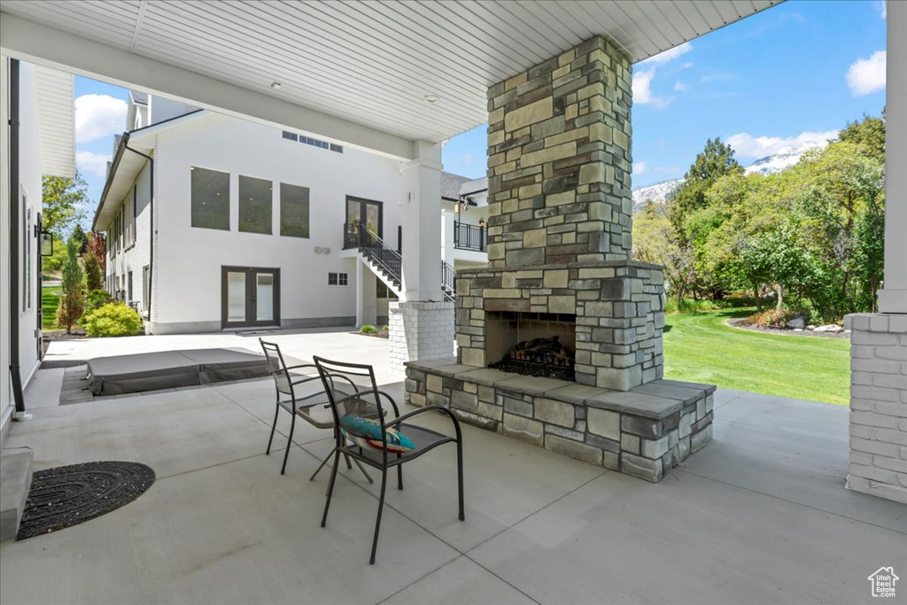 View of patio / terrace featuring an outdoor stone fireplace, french doors, and stairway
