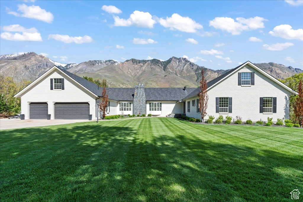 Traditional home featuring a mountain view, a front lawn, driveway, and an attached garage