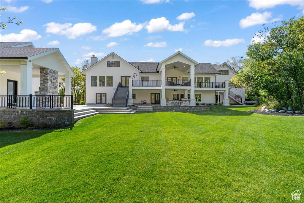 Rear view of property featuring stairs, ceiling fan, stucco siding, a patio area, and a lawn