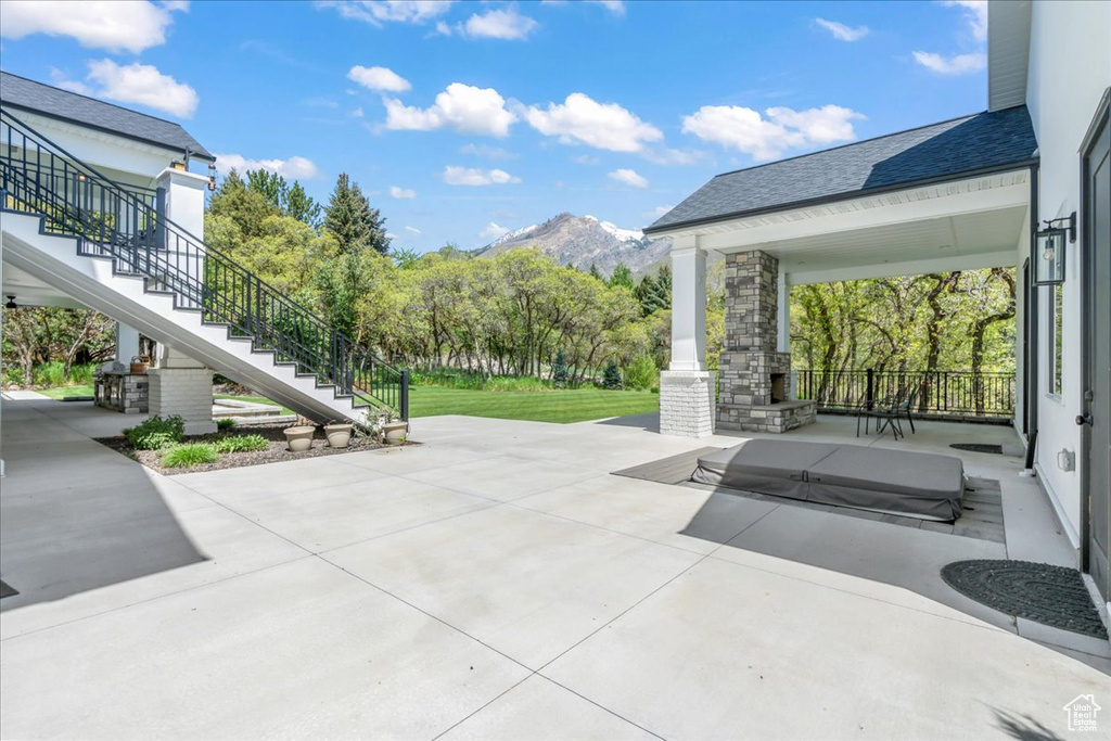 View of patio / terrace featuring stairway, an outdoor stone fireplace, and a mountain view