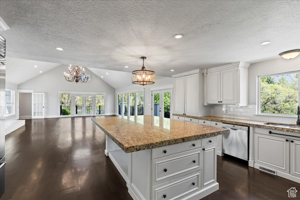 Kitchen featuring stainless steel dishwasher, a chandelier, open floor plan, french doors, and dark wood-type flooring
